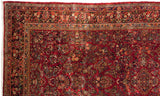Elaborate floral and boteh designs within the navy blue border of a vintage American Sarouk carpet.