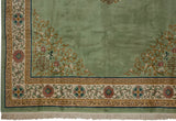 Corner of Japanese Peking rug: sage green field, ivory border, scrolling floral pattern, and fringe.