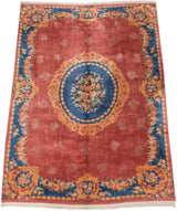 Angled view of a vintage Aubusson carpet, highlighting its roundel medallion and blue floral border.