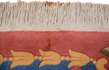 Detail of minor rust staining on the ivory fringe and raspberry wool pile.