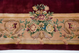 Japanese Savonnerie rug border with dense rose bouquets and scrolling vinery on deep red.