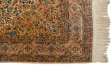 Corner of a vintage Isfahan rug with dense floral borders, intact selvage, and cream fringe.