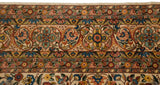 Intricate floral border of a vintage carpet, showing full pile in saffron, blue, and mint green.