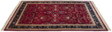 Angled view of a fine Indian Sarouk carpet with a red floral field and navy border.