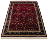 Angled perspective of a fine Sarouk carpet featuring a red floral field and a dark navy blue border.