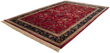 Fine Indian Sarouk carpet from an angle, showing its red floral field, navy border, and ivory fringe.