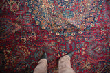 A downward view of the Tabriz rug's dense millefleur pattern in cherry red and navy blue.