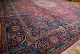 Low-angle view of a Tabriz carpet's cherry red field and detailed navy blue lotus flower border.