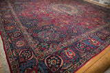 Angled view showcasing the navy blue border with serrated leaves on a vintage Tabriz carpet.