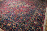 Angled view of a Tabriz rug corner with a navy lotus flower border and dense cherry red field.