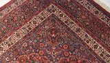 Intricate floral designs within the multi-layered corner borders of a vintage Persian Meshed carpet.