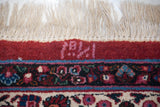 Weaver's inscription in raspberry tones on the cherry red border of a collectible Persian Meshed carpet.