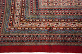 Intricate borders of a vintage Mir Sarouk rug corner in cherry red, ivory, and navy blue.
