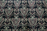 Curvilinear relief outlines the Damask floral motifs in aubergine, ivory, and charcoal.