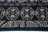 Curvilinear relief of the Damask-inspired design in aubergine, ivory, and charcoal on the black pile.