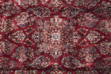 Deep black cherry red wool pile with dense floral sprays of powder blue and ivory blossoms.
