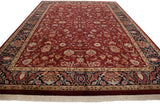 Rich wine red field with scrolling tendrils, detailed navy blue floral border, and ivory fringe.