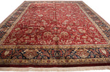 Angled view of the Sarouk design carpet's dense floral pattern, rich red field, and navy border.