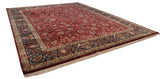 Angled view of a fine Indian Mohajeran Sarouk carpet, showcasing its plush wine-red field and navy blue border.