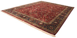 Angled view of a vintage Mohajeran Sarouk rug showing its rich red field and navy floral border.