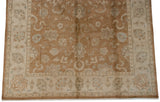 Vintage Indian Oushak rug corner showing ivory border with floral vinery, bronze field, and fringe.