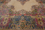 Close-up of Kerman carpet's Rococo blossomed floral sprays in ivory, blue, and pink.