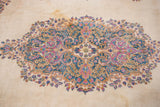 Kerman carpet's Rococo floral medallion in blue, pink, gold, on an ivory field with subtle tonal shifts.