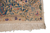Detail of vintage Kerman carpet's ivory fringe and border with blue, pink, and gold Rococo floral motif.