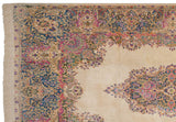 Vintage Kerman carpet corner with Rococo floral motifs, blue, pink, and ivory fringe.
