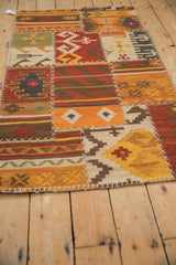 Warm-toned geometric panels with reciprocating motifs and visible white cross stitches on a patchwork kilim.