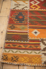 Geometric patchwork kilim panel showing brick red, orange patterns, and white cross-stitch seams.