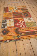 Close-up of patchwork kilim panel showing brick red rams horn blossom, olive geometric gul, and cross stitch.