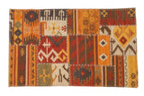 Patchwork kilim rug with geometric panels in warm orange, red, and brown, joined by white cross-stitching.