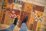 Overhead view showing the scale of a geometric patchwork kilim with visible cross-hatch stitching.