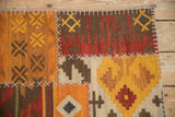 Corner of a patchwork kilim showing raised ivory stitches connecting warm-toned geometric panels.