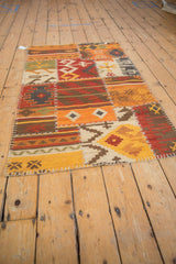 Warm-toned geometric panels of a patchwork kilim rug connected by raised ivory cross-stitching.