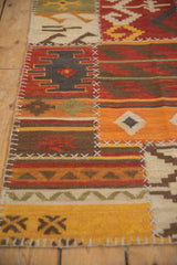 Raised cross-hatch stitches join geometric panels of red, orange, and brown on a patchwork Kilim.
