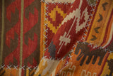 Raised cross-hatch seams connecting geometric panels of a warm-toned patchwork kilim.