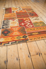 Warm-toned patchwork kilim rug with simulated white cross-hatch seams and primitive geometric motifs.