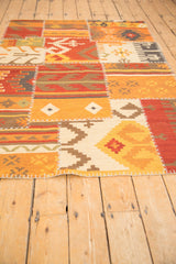 Geometric panels with white cross-stitch seams on a warm patchwork Kilim rug edge.