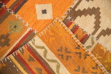 Raised cross hatch stitches on varied orange and brown patchwork kilim rug panels.