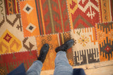 Warm palette geometric panels with white cross-stitch seams on a Kilim rug.