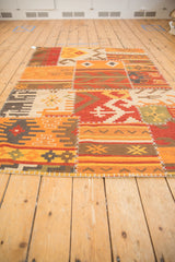 Vibrant geometric guls and primitive patterns with white cross-stitch seams on a patchwork kilim.