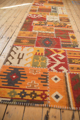 Patchwork Kilim runner with geometric primitive designs, warm palette, and white cross-stitch seams.