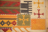 Saffron rams horn motif on olive green kilim panel with white cross hatch stitches.