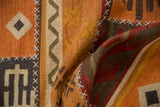 Folded patchwork kilim runner showing geometric patterns and raised white cross-hatch stitches.
