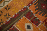 Textured detail of orange, red, and brown kilim patchwork with prominent cross-stitch seams.