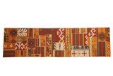 A new patchwork kilim runner with geometric and primitive panels in a warm palette of red, orange, and brown.