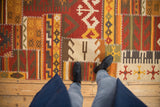 A view looking down at the warm-toned geometric panels and raised cross-hatch stitches of a patchwork kilim runner.