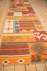 Long angle view of a patchwork kilim runner showing its geometric panels and raised stitching.